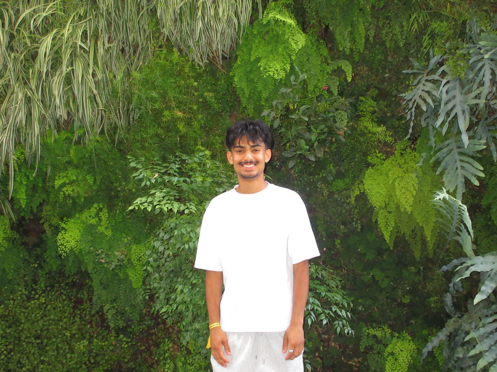 Ayaan standing in front of a green garden wall